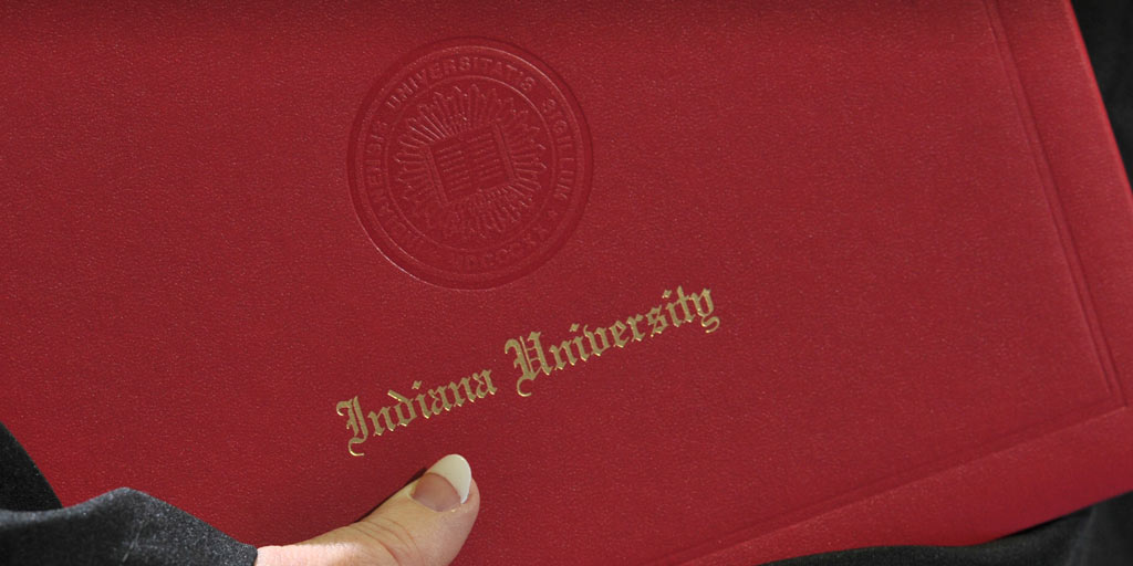 The Indiana University seal hangs above graduates at commencement